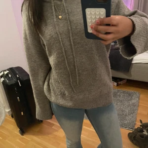 Grå stickad hoodie  - Mysig grå stickad hoodie från Lindex i storlek XS. Tröjan har huva med snörning, långa ärmar och ribbade muddar. Perfekt för kyliga dagar och enkel att matcha med jeans eller leggings.