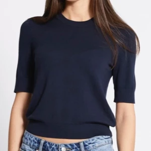 Mörkblå stickad topp med kort ärm - En stilren mörkblå stickad topp med rund halsringning och korta ärmar. Perfekt till jeans eller kjol för en clean look. Mjuk och skön känsla tack vare det stickade materialet. Enkel att matcha och passar till många olika stilar.