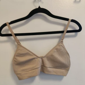 Beige ribbad linnetopp - Säljer en beige ribbad linnetopp med smala axelband och mjuk, stretchig känsla. Perfekt för lager-på-lager eller som den är till jeans eller kjol. Enkel och stilren design som passar till många olika looks.