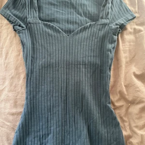 Mörkblå ribbad topp - Snygg mörkblå ribbad topp med v-ringad hals och korta ärmar. Den har en figursydd passform. Finns ett litet mindre hål där av priset.💕