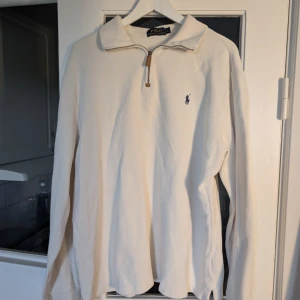 half zip tröja Polo Ralph Lauren - Snygg beige långärmad tröja från Polo Ralph Lauren med klassisk krage och half zip-dragkedja. Tröjan har en broderad marinblå logga på bröstet och är tillverkad i mjuk bomull. Perfekt för en clean och stilren look.