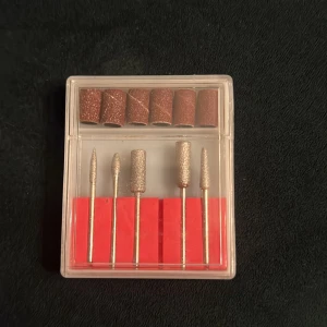 Set med nagelfilar och sliphuvuden - Ett oanvänt kit med fem olika metallsliphuvuden och sex bruna slipband för elfil, perfekt för nagelvård och formning. Kommer i en genomskinlig plastask. 