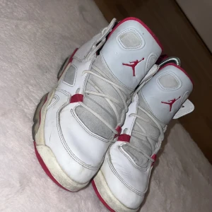 Vita och röda Nike Air Jordans - Säljer ett par vita och röda Nike Air Jordans med klassisk Jumpman-logga på plösen. Skorna har snörning och en platt sula med röd och gul detalj undertill. Perfekta för dig som gillar streetwear och sneakers med retrostil.