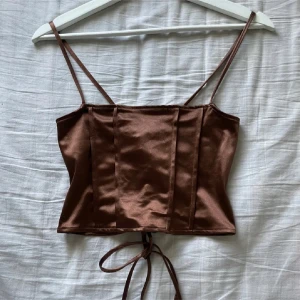 Snygg kroppad korsett/topp - Snygg brun topp 🌟🌟 Aldrig använd så i ny skick! Den är stretchig och justerbar där bak, se bilderna. Klippte bort lappen förut, gissar på storlek XS/S 🤩 Sjukt snyggt till fest, vardag eller varma dagar 😙
