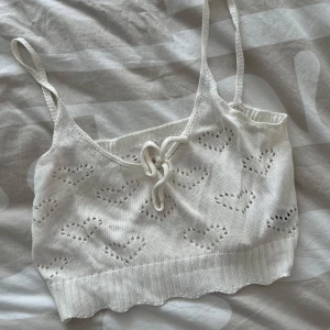 Vit stickad linnetopp med hjärtmönster - Supersöt vit stickad linnetopp med små hjärtan och knytning framtill. Toppen har smala axelband och en croppad passform, perfekt för varma dagar. Från shein