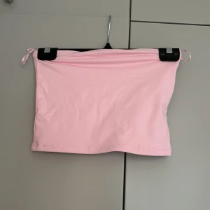 Ljusrosa tubtopp från FB Sister - Säljer en ljusrosa tubtopp från FB Sister. Toppen är ärmlös och har en enkel, stilren design utan mönster eller detaljer. Perfekt att matcha med jeans eller kjol för en trendig look.