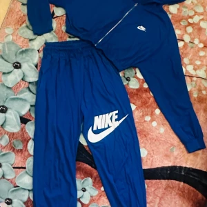 Nike träningsset i blått – som nytt⭐️⭐️ - Superfint och bekvämt träningsset från  i härlig blå färg. Består av zip-hoodie och byxa med resår. Endast använt en gång – i nyskick, helt utan fläckar eller skador. Passar perfekt till träning eller vardag.