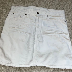 Lågmidjad vit jeanskjol  - Säljer denna vita jeanskjol, då den är för liten. Köpt begagnat så vet ej vart den är ifrån. Längd 41cm och i storleken 40. Superfin till sommaren! 