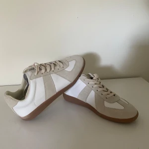 Maison Margiela - 👟 Maison Margiela GATs (German Army Trainers) - Storlek 42 👟  *   Skick: aldrig använda! *   Storlek: 42 – Perfekt om du vill ha en stilren och bekväm sneaker. *   Beskrivning: Säljer ett par grymma Maison Margiela GATs. Minimalistisk design och hög kvalitet. Perfekt för att lyfta vilken outfit som helst! *   Info: Ingen kartong, men original dustbag ingår. *   Frakt: Snabb frakt! *   Hör av dig om du har frågor eller vill ha fler bilder!