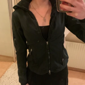 Svart jacka med luva - Säljer en svart jacka med huva och flera dragkedjor, både framtill och på ärmen. Jackan har en figurnära passform och en sportig look säljer för att börjar att bli liten för mig 💕