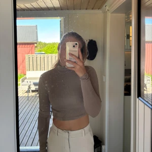 Beige croppad polotröja med snörning i ryggen - Säljer en beige croppad polotröja med lång ärm och öppen rygg med snygg snörningsdetalj. Perfekt för dig som vill ha något trendigt och unikt i garderoben!