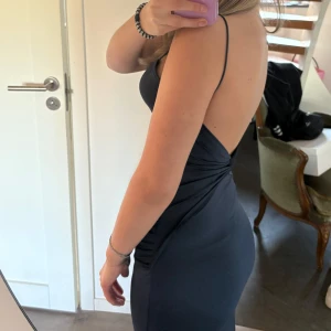 Mörkblå långklänning med slits - Säljer en elegant mörkblå långklänning med smala axelband och öppen rygg. Klänningen har en tight passform och en snygg slits på sidan.💓Har använt enstaka gånger💓