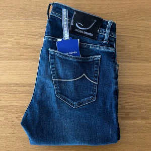 Jacob Cohen 688 30 - Supersnygga Jacob cohen jeans i modellen 688 som liknar Bard i de nyare modellerna. Storlek 30. De är handgjorda i Italien med en sjukt snygg lite mörkare tvätt och väldigt fina detaljer. De är i mycket bra skick och har inga defekter. Nypriset på dessa är runt 5200, mitt pris 950. Hör av vid några frågor!     Bredd midja: 40cm  Bredd vid låret 23cm  Innerbenslängd 76cm  Total längd 100cm