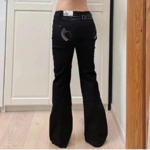 Svarta bootcut jeans med strasstenar och bälte - Säljer ett par svarta bootcut jeans med snygga strasstenar på bakfickorna Jeansen har låg midja och utsvängda ben, perfekt för en trendig look. Jag köpte originelt jeansen för 900kr Säljer för att de inte passade. Kontakta gärna för mått och för att diskutera priset💞