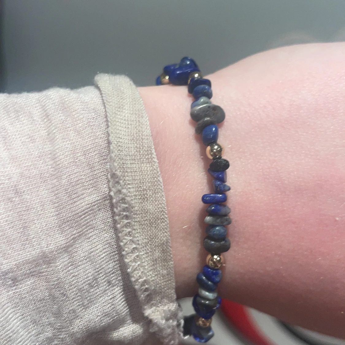 Blått armband med stenar och gulddetaljer