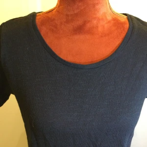 Svart t-shirt med snörning i ryggen M - En svart t-shirt med rund halsringning och korta ärmar. Baksidan har en snygg snörningsdetalj som ger en unik look. Perfekt för dig som vill ha en enkel men ändå speciell t-shirt i garderoben. Topp med snörning på ryggen Bomull Lite längre i bak