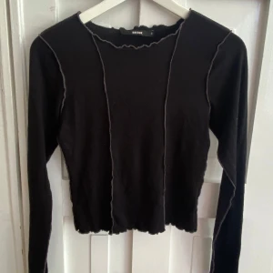 Svart långärmad topp från Bik Bok - Svart långärmad topp från Bik Bok med råa kanter och dekorativa sömmar. Modellen har en tight passform 🖤