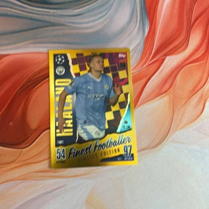 Finest Footballer Limited Edition - Haaland - Samlarbild med fotbollsspelaren Haaland i Manchester Citys ljusblå matchtröja. Kortet har guldram, holografiska detaljer och texten 'Finest Footballer Limited Edition'. Perfekt för fotbollsentusiaster och samlare.