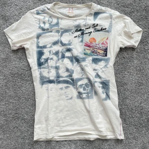 Vit t-shirt med tryck från Diesel - Vit t-shirt från Diesel med coolt grafiskt tryck av ansikten och färgglad broderad detalj på bröstet. Texten 'Mellow and Cool as Morning Sunshine' syns på framsidan. Rund halsringning och korta ärmar. Perfekt för en avslappnad stil.