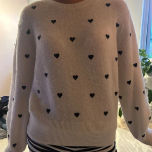 Vit stickad tröja med svarta hjärtan - Superfin vit stickad tröja från Other stories med små svarta hjärtan över hela. Tröjan har rund halsringning och långa ärmar✨✨