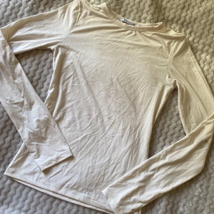 Beige långärmad topp från 157 - Enkel och stilren beige långärmad topp från 157. Modellen är figurnära med rund halsringning och tillverkad i mjuk bomull. Perfekt att styla med jeans eller kjol för en clean look. Endast använt en gång. Köpt för 100kr på rea.