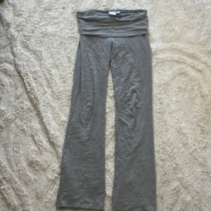 Grå yoga pants från Gina Tricot - Grå yoga pants från Gina Tricot med bred, låg midja och booutcut. Byxorna är gjorda i mjukt bomullsmaterial och passar perfekt för en chill och avslappnad stil.