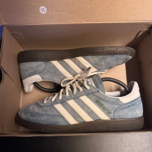 Adidas Spezial blå mockasneakers - Snygga Adidas Spezial sneakers i ljusblå mocka med vita detaljer och klassiska tre ränder på sidorna. Skorna har svart sula, snörning och vit hälkappa. Perfekta för dig som gillar retrostil och streetwear. Använda en del och limmat fast sulan där den lossnat