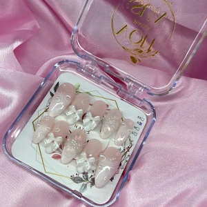 Cupid (S);Medium Almond - Superfina gelé press on-naglar i ljusrosa med glansig finish, dekorerade med vita 3D-rosetter, pärlor och glitterdetaljer. Naglarna är i en medium mandelformade och kommer i S: 15 mm, 11,5 mm, 12 mm, 11 mm, 9 mm. Perfekt för dig som vill ha en söt och trendig look.