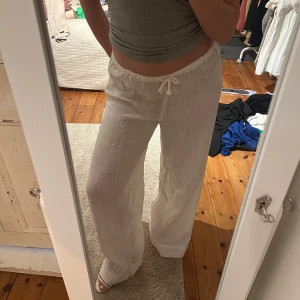 Vita linnebyxor från Nelly XS - Säljer ett par vita linnebyxor från Nelly i storlek XS. Byxorna har breda ben, hög midja och dragsko i midjan för skön passform. Lätta och luftiga med snyggt fall, perfekta för varma dagar. Stilren och enkel design som är lätt att matcha. Nyligen köpta från Nelly men dom är lite långa på mig (på bilderna har jag höga klackar 👠). Dom är endast provade en gång men jag tog bort prislappen. Modell Easy breeze pants💖