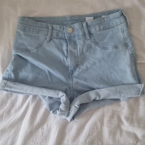 Ljusblå low waist jeansshorts - Snygga ljusblå jeansshorts från &Denim med klassisk femficksdesign och uppvikta benslut. Shortsen har bälteshällor, knapp och dragkedja framtill. Perfekta för varma dagar och enkel att matcha med allt.