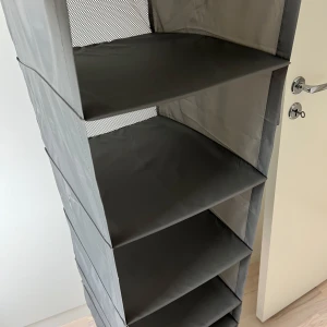 Vikbar hängförvaring i vitt - Säljer en praktisk vikbar hängförvaringar i grått. Perfekt för garderoben eller hallen, med flera hyllplan och meshdetaljer upptill. Tillverkade i lätt polyester och enkla att hänga upp på en stång eller krok. Köpt från Ikea namn Skubb. Nypris 99kr