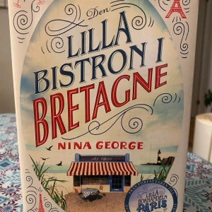 Den lilla bistron i Bretagne av Nina George - Inbunden bok! Fint skick!                                   Följ med till Frankrikes kust där Marianne, trött på sitt gamla liv, hittar gemenskap och nya möjligheter i en färgstark by.                       En berättelse om att våga börja om, njuta av livet och hitta sig själv – perfekt för dig som gillar feelgood och inspirerande resor.