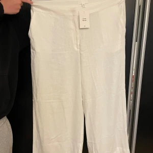 Vita linnebyxor från H&M wide fit - Snygga vita linnebyxor från H&M med relaxed wide fit och hög midja. Byxorna är tillverkade i en skön linneblandning som känns luftigt och fräscht. Perfekta för varma dagar när du vill ha en clean och stilren look.