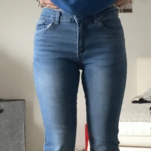 Blå bootcut jeans med detaljer - Snygga blå bootcut jeans med mid midja och coola detaljer på bakfickorna. Jeansen har klassisk femficksdesign och är tillverkade i stretchigt denim för en bekväm passform. Perfekta för dig som gillar en retroinspirerad look med lite extra edge.