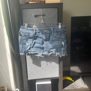 EDC by Esprit jeanskjol med slitningar - Snygg blå jeanskjol från EDC by Esprit med slitna detaljer och rå kant nertill. Klassisk femficksmodell med dekorativa bakfickor och tydliga kontrastsömmar. Perfekt för dig som gillar en edgy och avslappnad stil.