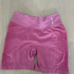 Rosa seamless träningsshorts DFYNE - Snygga rosa seamless shorts från DFYNE med hög midja och diskret mönstrad struktur på sidorna. Stretchigt material som sitter tight och formar sig efter kroppen, perfekt för gymmet eller löpning. Logga framtill i vitt och scrunch-detalj bak. Shortsen är nästan helt oanvänd och jag säljer för att jag har ingen andväning av dom