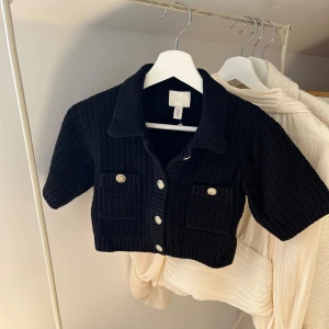 Svart stickad kofta från H&M - Svart stickad kofta från H&M med kort ärm och croppad passform. 