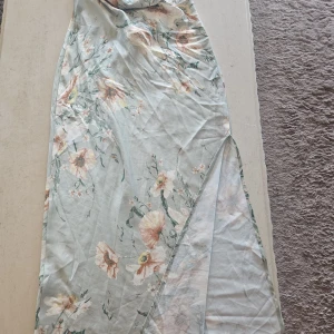 Blommig långklänning från SHEIN - Superfin långklänning från SHEIN i ljus pastellgrön ton med blommigt mönster. Klänningen har snörning i ryggen, slits på sidan och tunna axelband. Perfekt för sommarens alla tillfällen och ger en romantisk vibe.