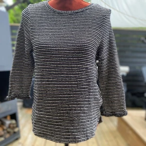 Svartvit randig tröja i bomull XS - Svart och beige randig tröja med 3/4 ärmar och rund halsringning. Tröjan har en texturerad yta. Lite längre bak! ﻿Uppvikta ärmslut ﻿L: 62 cm, bystvidd: 45 cm ﻿55% bomull, 45 % polyester  Inga bilder när den sitter på mig! Katter finns i hemmet!