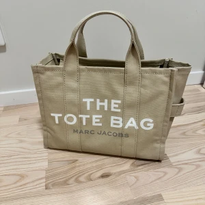 Beige Tote Bag från Marc Jacobs - Säljer min väska då jag inte har använt den ett tag, bara suttit där utan någon användning alls. Väldigt rymlig för dig som pluggar/använder det vardagligen. Passar att ha en dator i, men blir för tungt om du har massor med grejer i. Du kan ha det som axelremsväska vilket också är väldigt smidigt. Köpt från miinto.  Priset kan diskuteras!  Bevis finns om ni vill se det !!