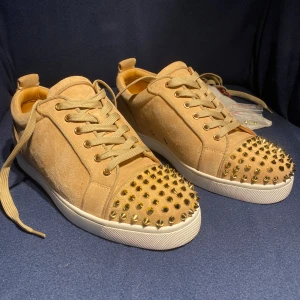 Christian Louboutin sneakers - Snygga beige sneakers från Christian Louboutin i mocka med guldiga nitar. skorna är i riktigt gott skick och ni får med extra nitar plus 2 stycken extra snören, box, dustbag osv ingår. skorna ser nästan som nya ut