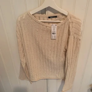 Beige ribbad tröja från Gina Tricot - Superfin beige långärmad tröja från Gina Tricot i ribbat material. Tröjan har en avslappnad passform och rund halsringning, perfekt att styla med jeans eller kjol. Materialet är mjukt och har en snygg struktur som ger en trendig look.
