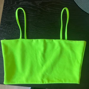 Neongrön bandeau topp - Säljer en neongrön bandeau topp med smala axelband. Märke parisian, köpt på jfr, storlek 38