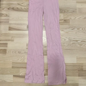 Folded leggings  - Säljer ett par ljusrosa bootcut byxor från Gina Tricot i mjukt bomullsmaterial. Byxorna har en enkel design utan fickor eller synliga detaljer och är perfekta för dig som gillar en clean och trendig look.
