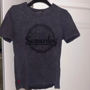 Mörkgrå Superdry t-shirt med paljetter - Fin T-shirt ifrån Superdry använd max 2 gånger. Storlek 38 men sitter som en S. 