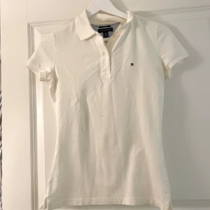 Vit piké t-shirt Tommy Hilfiger XS - Snygg vit piké t-shirt från Tommy Hilfiger i bomull. Myckt fint skick förutom en liten prick på framsidan, som knappt syns från långt håll🤍Kolla gärna in mina andra annonser, försöker bli av med allt så snart som möjligt 💝pris alltid förhandlingsbart, brukar gå med på de flesta prisförslag!😚 