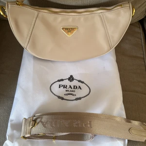 Beige Prada Re Edition - Säljer nu en helt oanvänd Prada väska som skulle vara en present. Förhållandet tog slut och nu behöver jag få den såld. Nypris ligger väskan runt 10 000 kr. Inget slitage eller liknande.                           Har du några andra funderingar? Bara hör av dig!