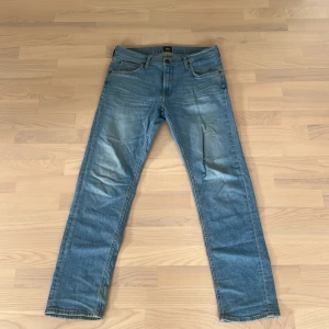 Ljusblå jeans från Lee - Säljer ett par klassiska ljusblå jeans från Lee med fem fickor och snygga slitningar. Jeansen har rak passform och normal midja, tillverkade i tåligt denimtyg. Perfekta till en avslappnad stil och funkar året runt.