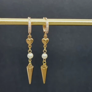 Guldiga örhängen med pärla och hjärta - Snygga guldiga örhängen med små hjärtan, vit pärldetalj och spetsig konformad hängande del. Ringen har glittriga stenar som ger extra bling. Perfekt för dig som gillar att sticka ut med coola detaljer och elegant vibe.