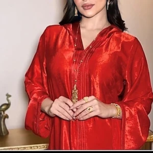 Röd långklänning med v-ringning - Elegant röd långklänning med v-ringad hals och vida ärmar. Perfekt för en glamorös kväll. Klänningen har en glansig finish som ger en lyxig känsla.